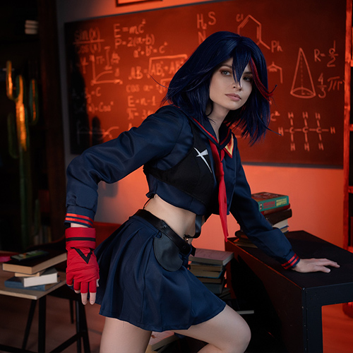 Ryuko Matoi cosplay character leaning confidently on a desk, wearing her signature navy and red school uniform in a classroom scene. The setting is filled with chalkboards covered in scientific equations and books stacked on shelves, all under a warm, orange-tinted light that highlights Ryuko's intense and determined expression