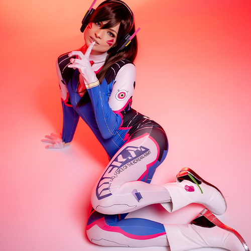This striking D.Va cosplay captures the Overwatch hero's bold and playful spirit against a vibrant orange-pink gradient backdrop. The detailed bodysuit with Korean military insignias and the iconic bunny logo highlights the precision of the character design. D.Va's signature headphones and confident pose exude charm and attitude, making this a perfect homage to the beloved Overwatch character.