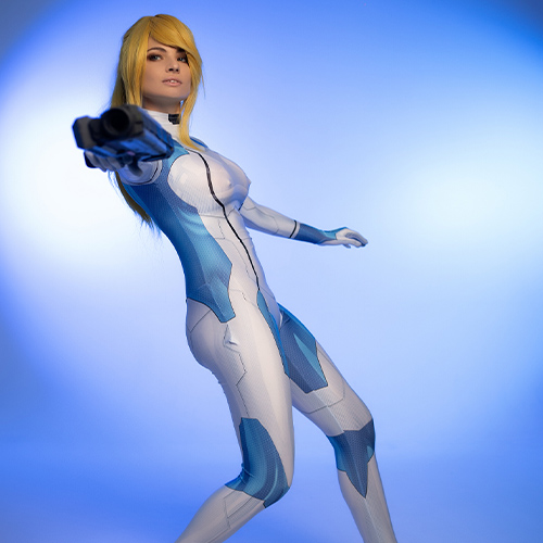 The Zero Suit Samus cosplay radiates power and precision, capturing the essence of the Metroid series protagonist. The striking blue tones of the suit, complemented by the bold aiming pose, reflect Samus Aran's fearless attitude and unmatched combat skills. The addition of high heels adds a sleek, stylish twist while maintaining the character’s iconic look. Perfectly illuminated against a gradient blue background, this portrayal is a true celebration of Nintendo's legendary intergalactic bounty hunter.