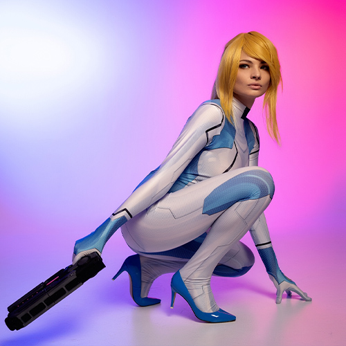 This dynamic Zero Suit Samus cosplay highlights the character's agility and strength from the Metroid franchise. The pose emphasizes a ready-for-action stance, with the iconic blue suit's sleek design perfectly adapted to showcase its futuristic appeal. The striking combination of high heels and the powerful arm cannon balances elegance with combat readiness. The vibrant gradient backdrop of blue and pink adds energy and depth, creating a visually captivating tribute to Samus Aran's legendary role as a fearless intergalactic bounty hunter.