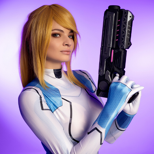 This close-up Zero Suit Samus cosplay highlights the elegance and power of the Metroid character. The vibrant purple background contrasts beautifully with the sleek design of the iconic blue suit, accentuating the character’s futuristic aesthetic. The detailed arm cannon and determined gaze convey Samus Aran’s readiness for battle, making this an exceptional portrayal of one of gaming’s most beloved heroines.