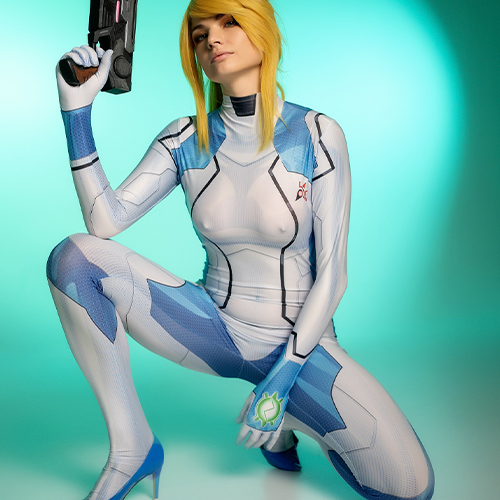 The bold stance of this Zero Suit Samus cosplay highlights the strength and confidence of the legendary Metroid protagonist. The intricate detailing of the suit, paired with the accurate replica of her signature weapon, emphasizes the dedication to authenticity. Against a striking turquoise backdrop, the ensemble radiates the essence of Samus Aran’s heroic and formidable presence in the galaxy. This photo is a must-see for fans of Nintendo's classic Metroid series.