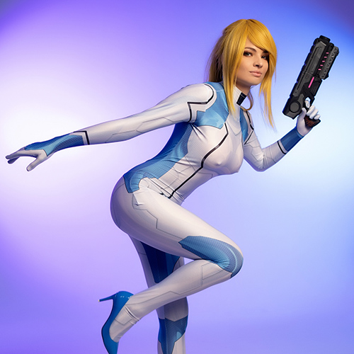 This dynamic Zero Suit Samus cosplay captures the agility and grace of the Metroid heroine in action. The sleek design of the bodysuit, combined with the vibrant blue heels and her iconic weapon, showcases her readiness for battle. The soft purple backdrop accentuates the futuristic and adventurous atmosphere that defines the Metroid universe. A perfect homage for fans of the legendary bounty hunter Samus Aran.