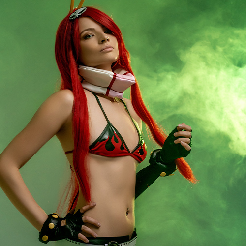 Beautiful Yoko Littner cosplay from Tengen Toppa Gurren Lagann, showcasing her flame-patterned bikini, vibrant red hair, and confident stance against a dynamic green smoke background. Perfect for fans looking for Yoko Littner cosplay inspiration or anime character photography