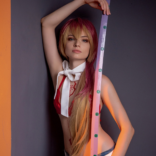 Captivating Shura Kirigakure cosplay from Blue Exorcist, showcasing her vibrant long red and blonde hair, red top, and denim shorts, posing confidently with her iconic katana. A must-see for fans looking for creative Blue Exorcist cosplay inspiration