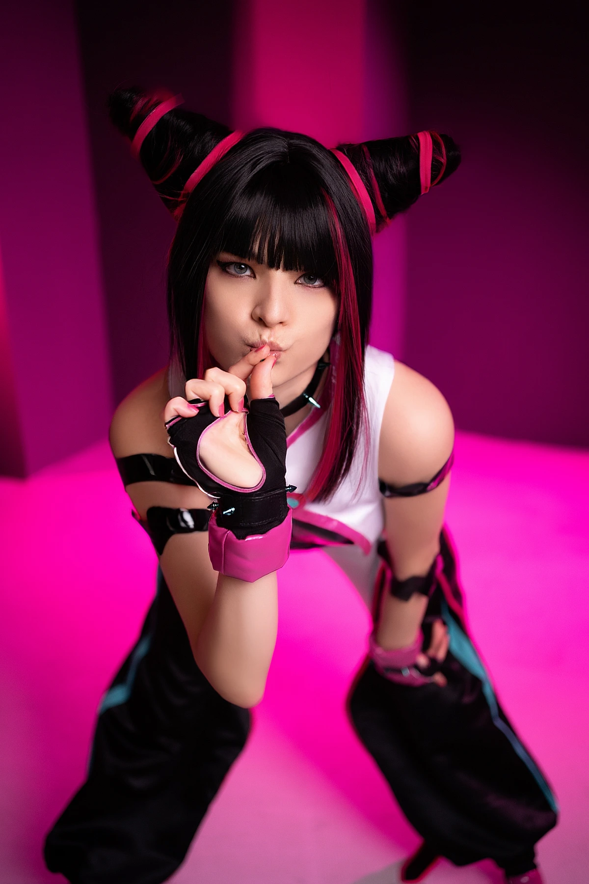Juri Han cosplay close-up portrait, finger on lips gesture, pink neon studio lighting, horn buns hairstyle, Street Fighter villain
