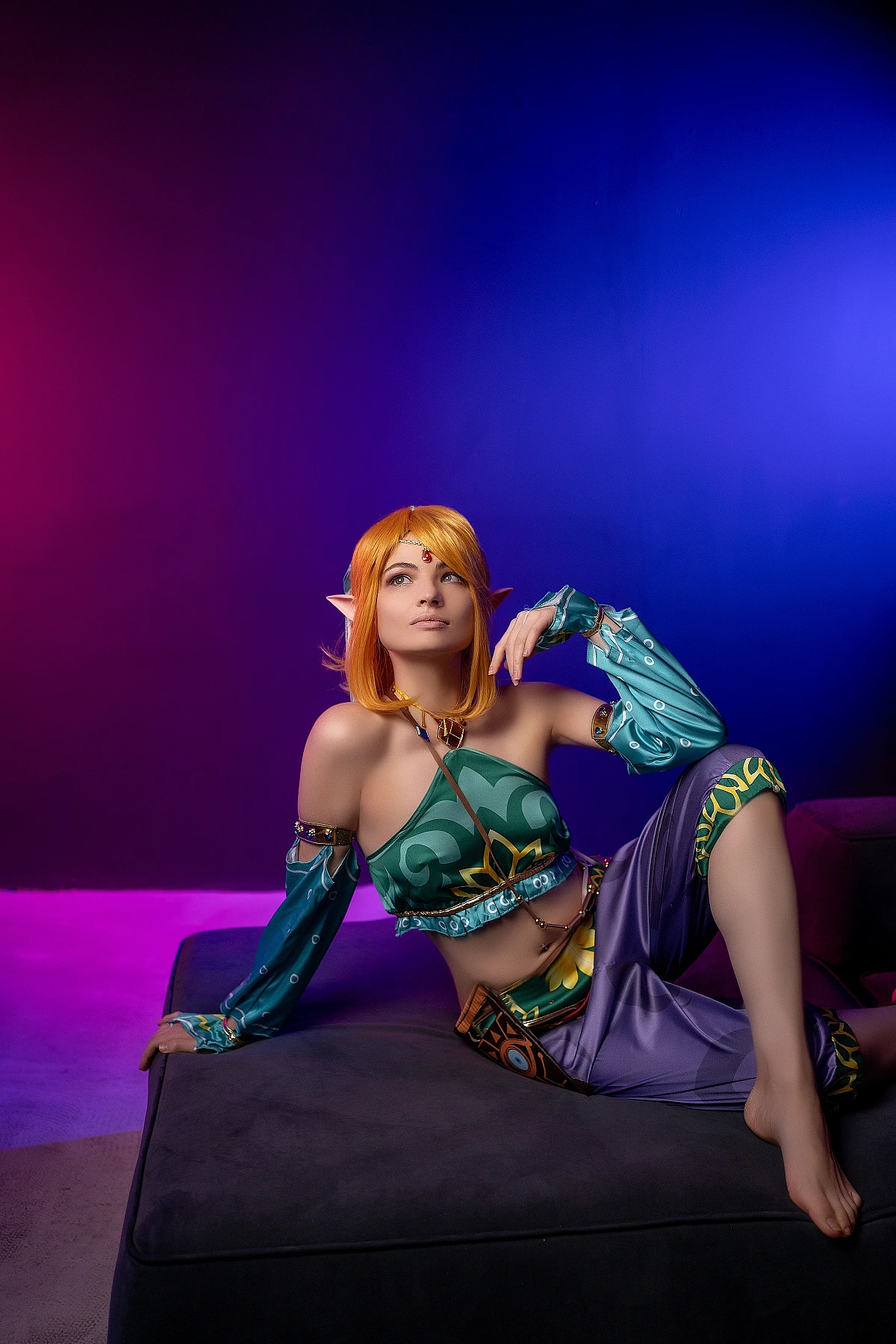 Gerudo Link cosplay seated on ottoman with neon purple-blue gradient