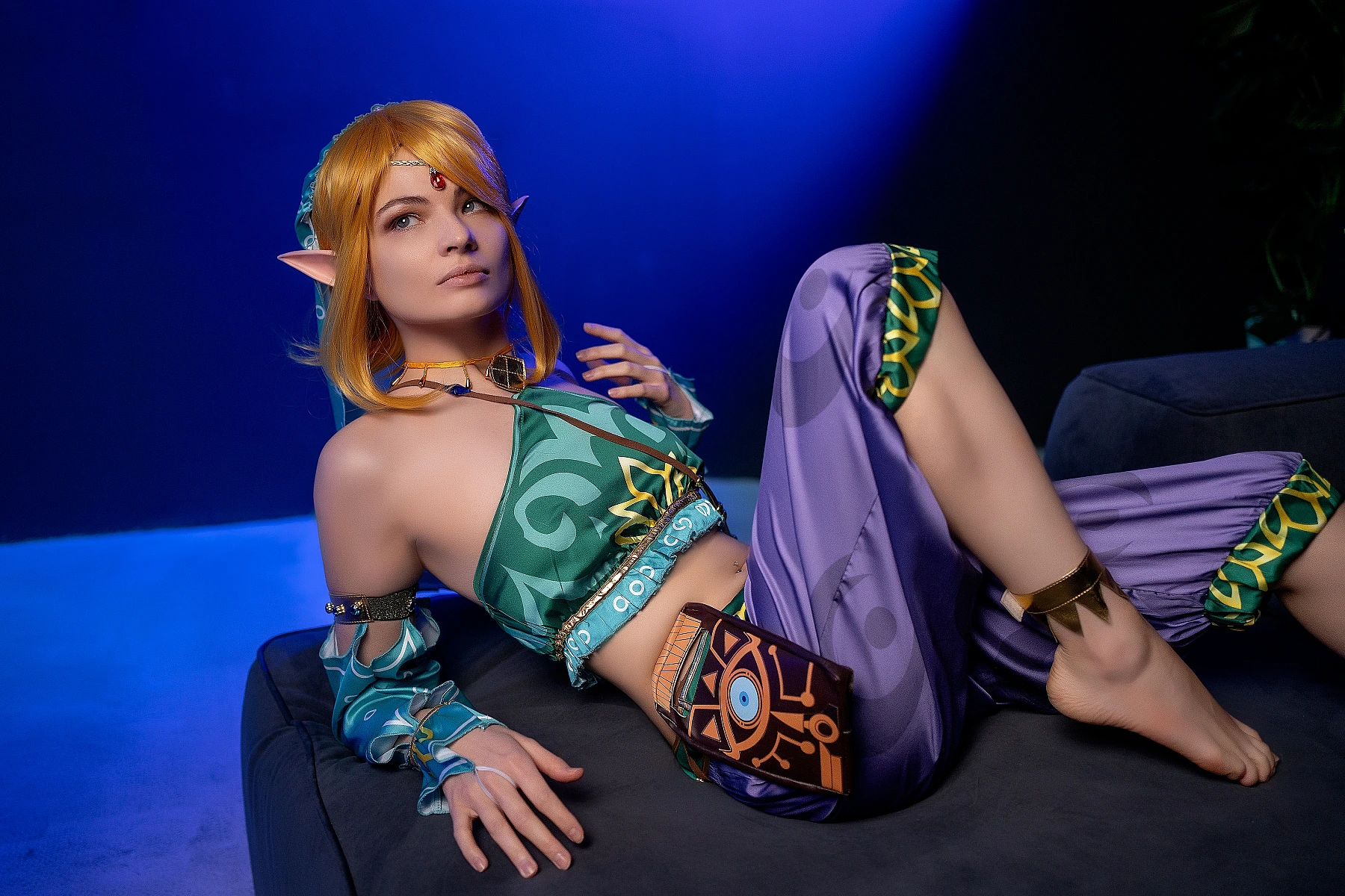 Gerudo Link cosplay reclining with teal glow and Sheikah eye pouch