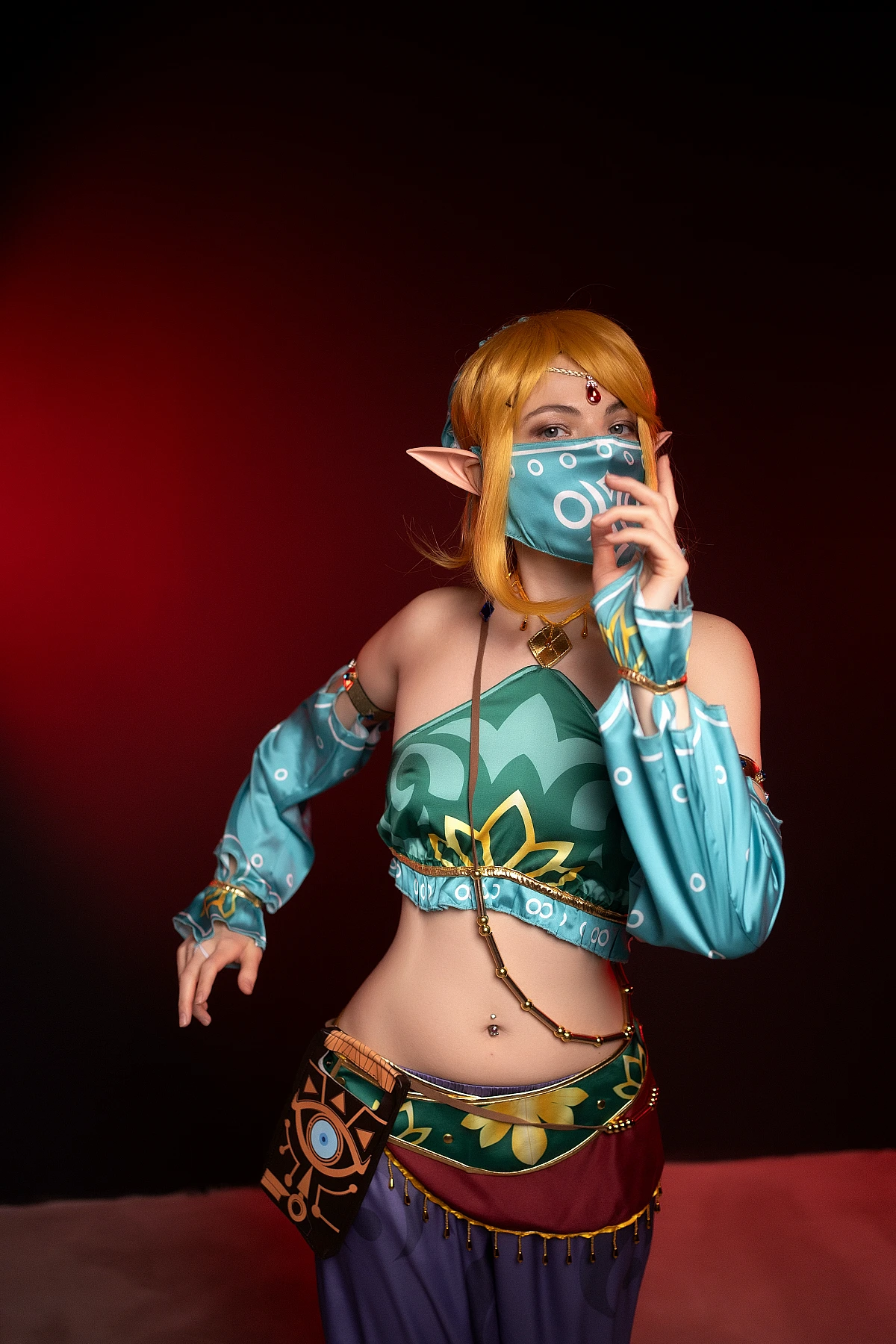 Gerudo Link cosplay standing with veil mask on red studio background