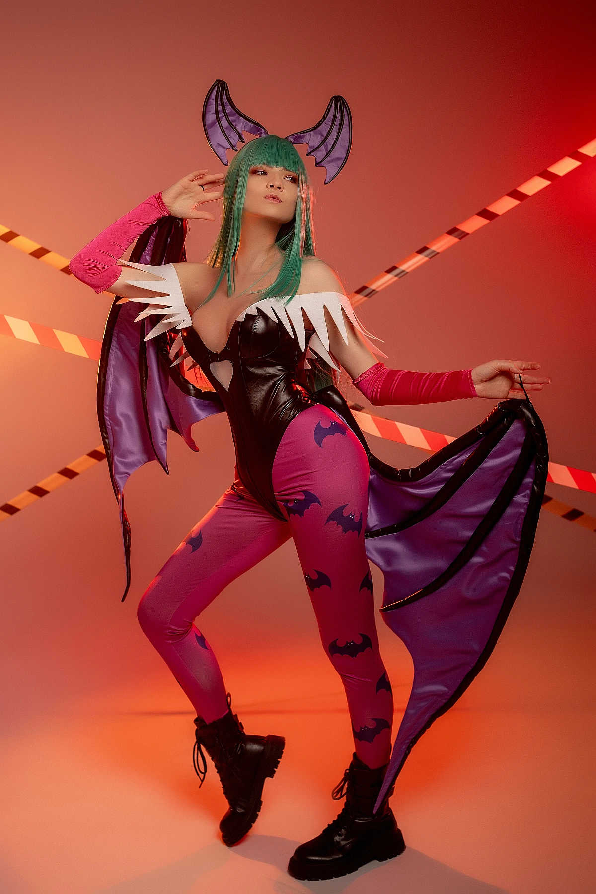 Elegant Morrigan Aensland cosplay with poised stance, warm red-orange studio lighting, draped succubus wings, glossy bodysuit
