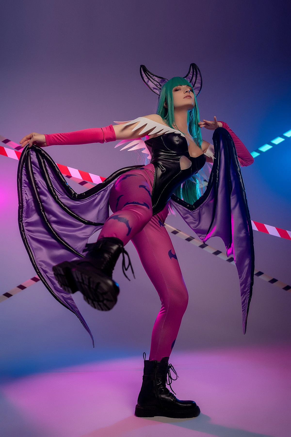 Dynamic Morrigan Aensland cosplay pose with raised leg, fully spread bat wings, violet-blue neon studio lighting