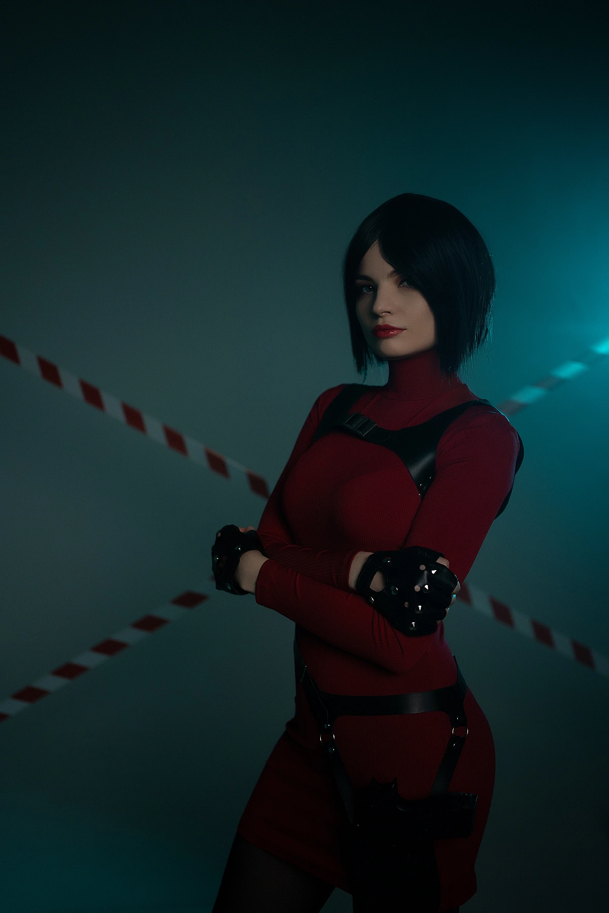 Ada Wong cosplay standing crossed arms red outfit black gloves harness blue rim light cold gaze
