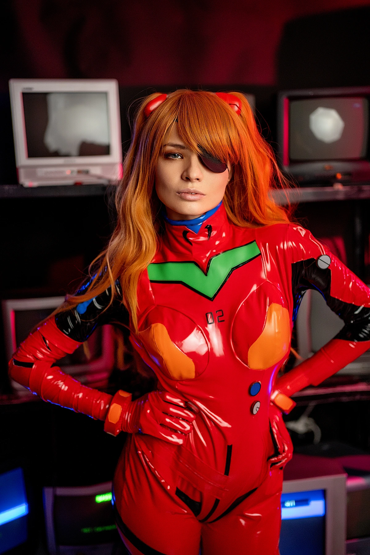 Asuka Langley plugsuit cosplay portrait with eyepatch, surrounded by glowing CRT monitors in dark cyberpunk studio with neon green and orange lighting