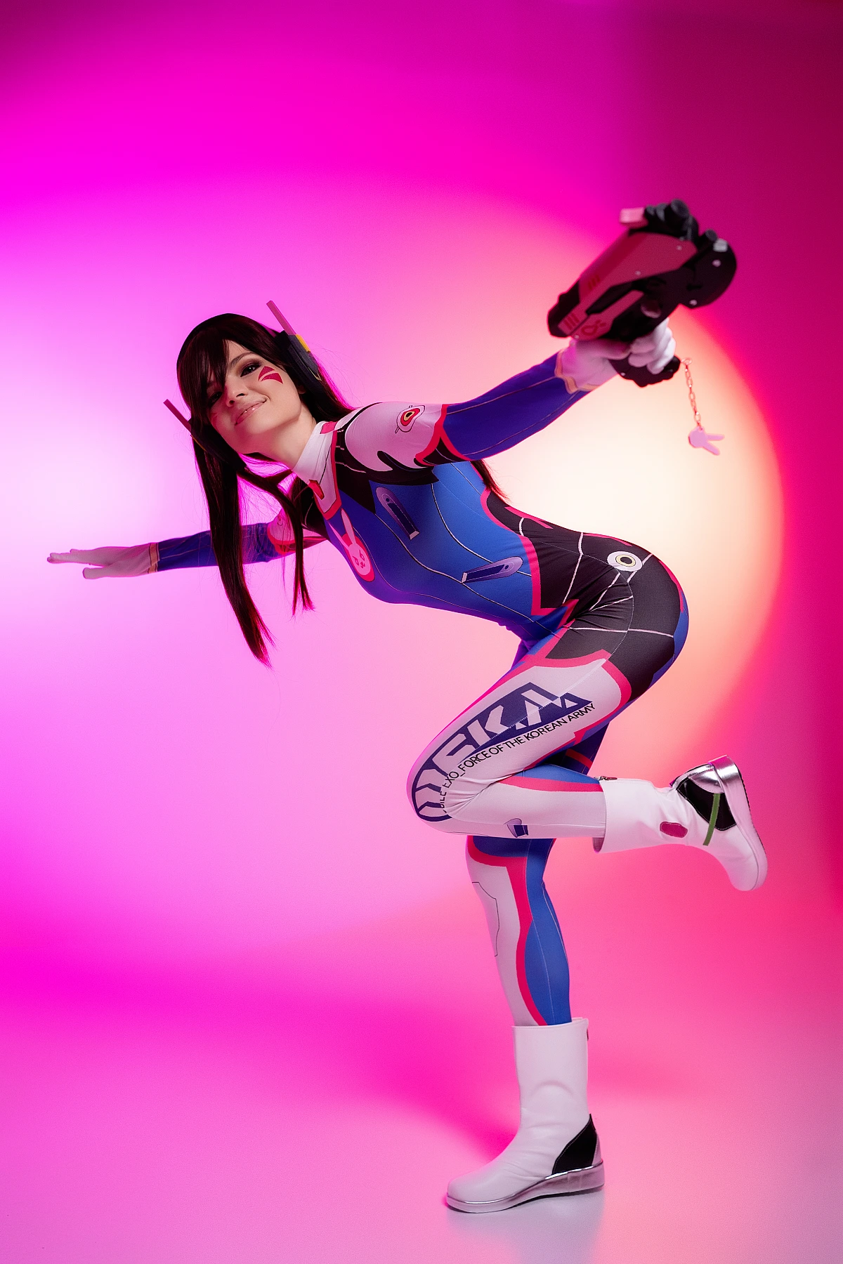 D.Va Overwatch cosplay one leg balance dynamic pose arms extended blaster magenta neon studio athletic