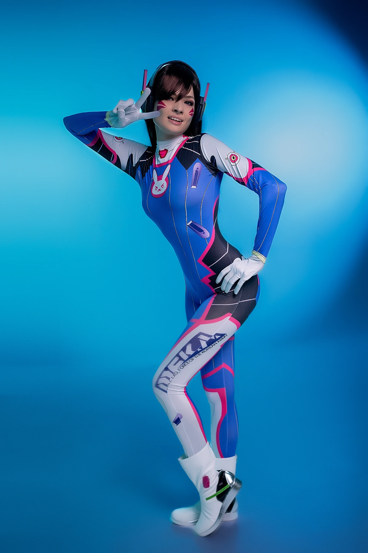 D.Va Overwatch cosplay standing full body peace sign confident pose blue gradient studio professional portrait