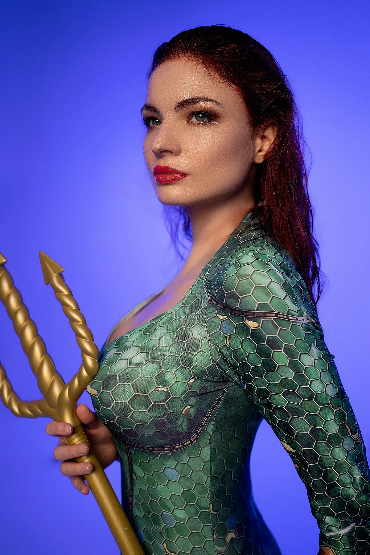 Profile close-up Mera cosplay holding golden trident with emerald scale costume and red hair