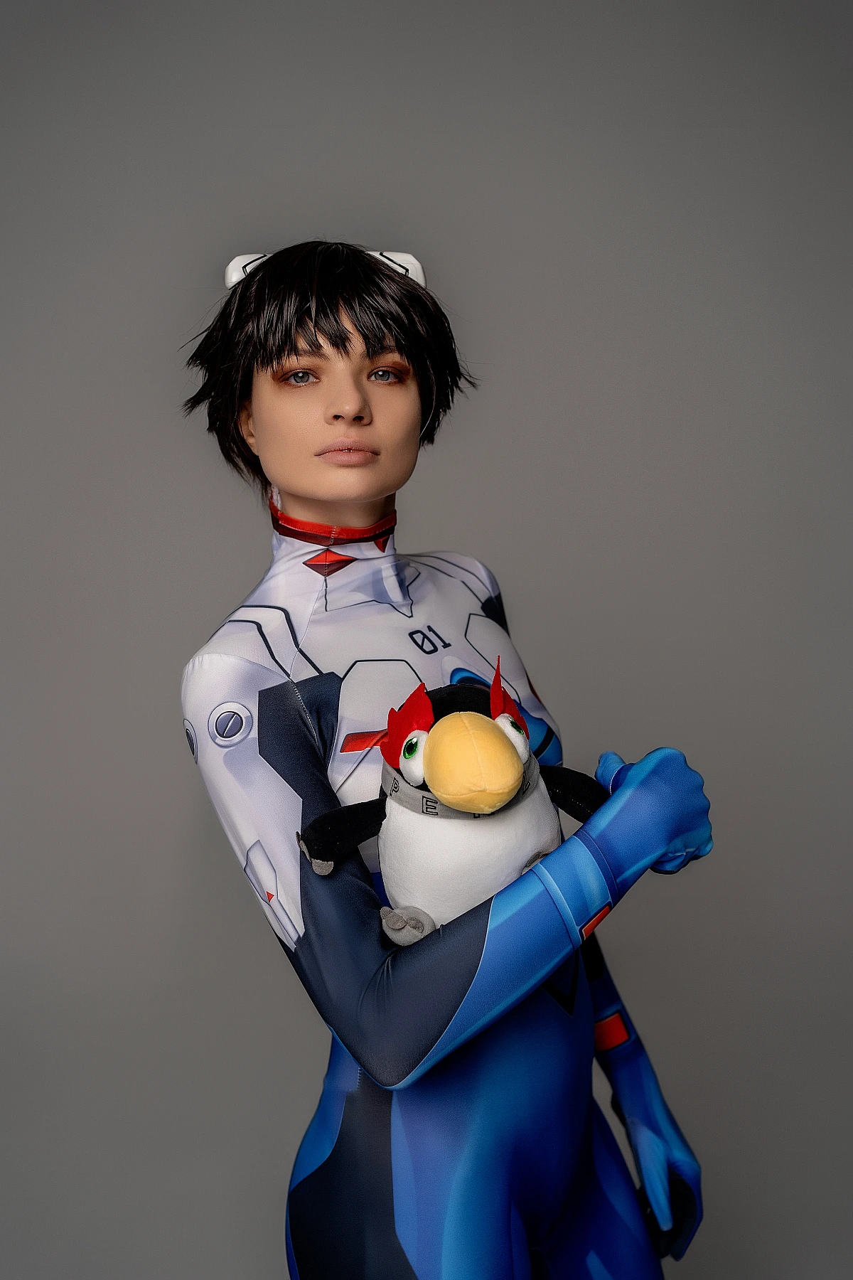 Shinji Ikari cosplay portrait with Pen Pen plush toy, blue plugsuit, androgynous anime cosplay, soft studio lighting