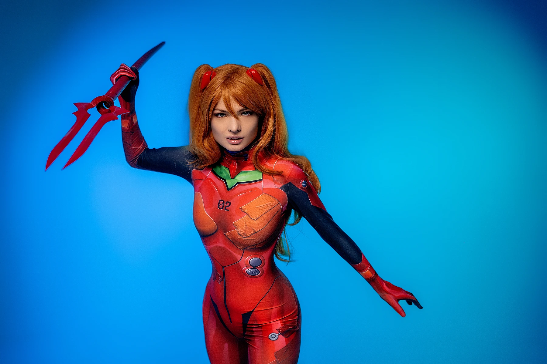 Asuka Langley cosplay raising spear in red plugsuit against neon blue background
