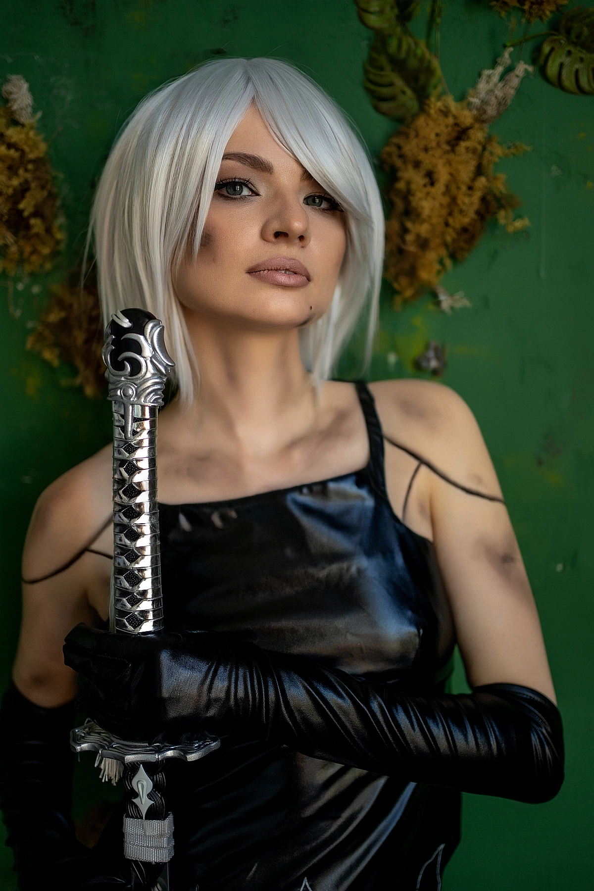A2 cosplay NieR Automata close portrait, white bob hair, glossy black outfit, katana sword hilt detail, calm intense expression, muted green textured wall