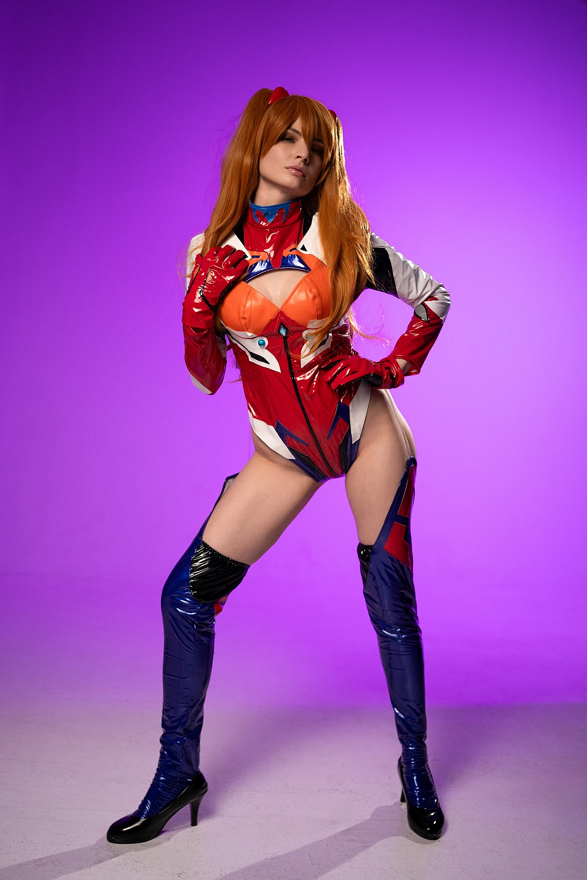 Asuka Langley power pose cosplay in latex plugsuit on purple studio background