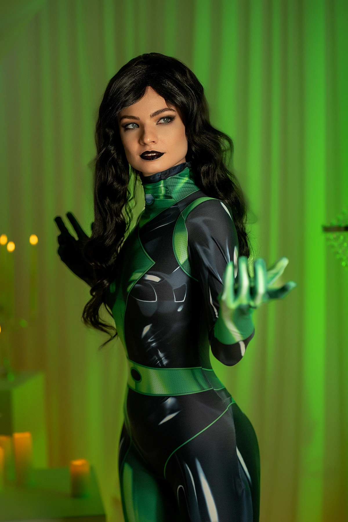 Shego cosplay full-length pose, green-black bodysuit, emerald curtain, hands extended