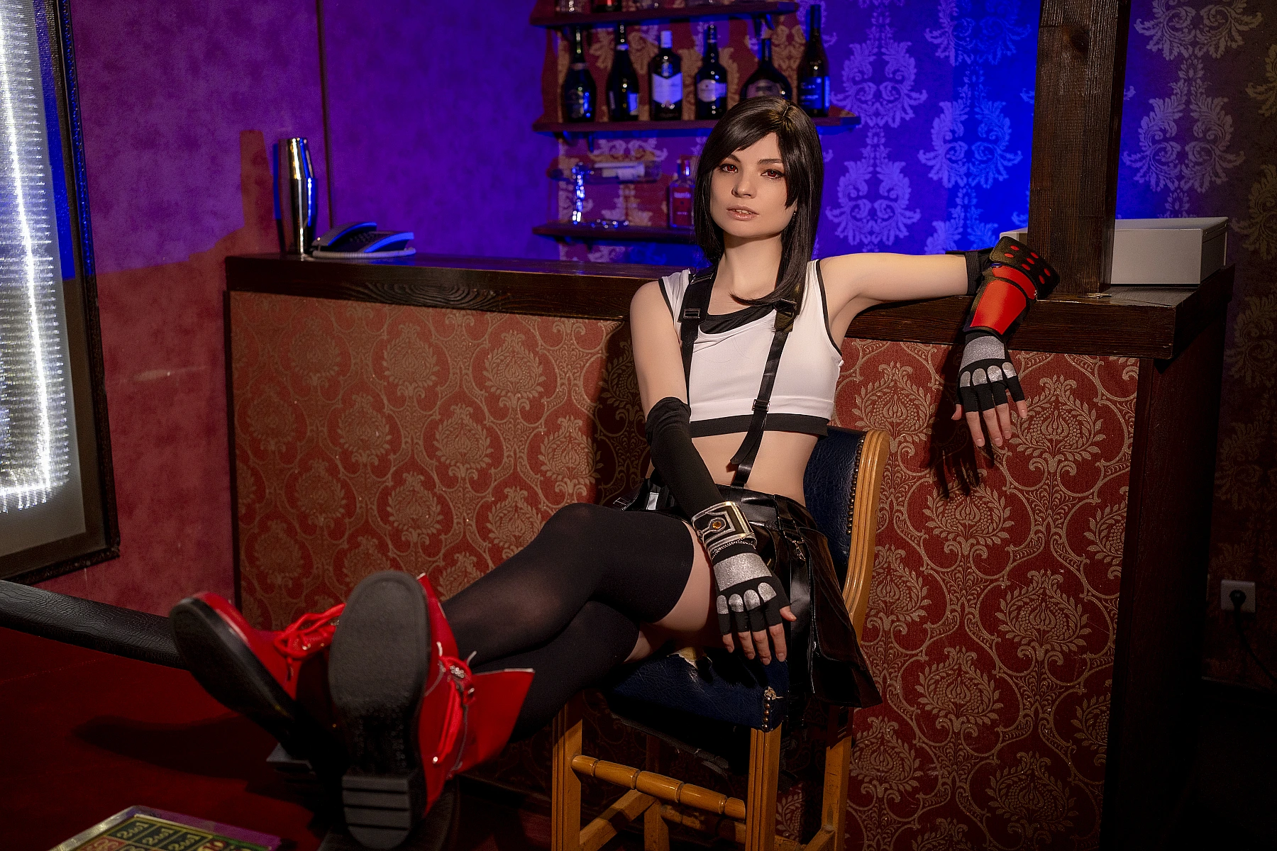 Tifa Lockhart cosplay late night relaxed bar pose, legs extended, FF7 costume with red boots and dark hosiery, layered warm cool lighting, 7th Heaven interior