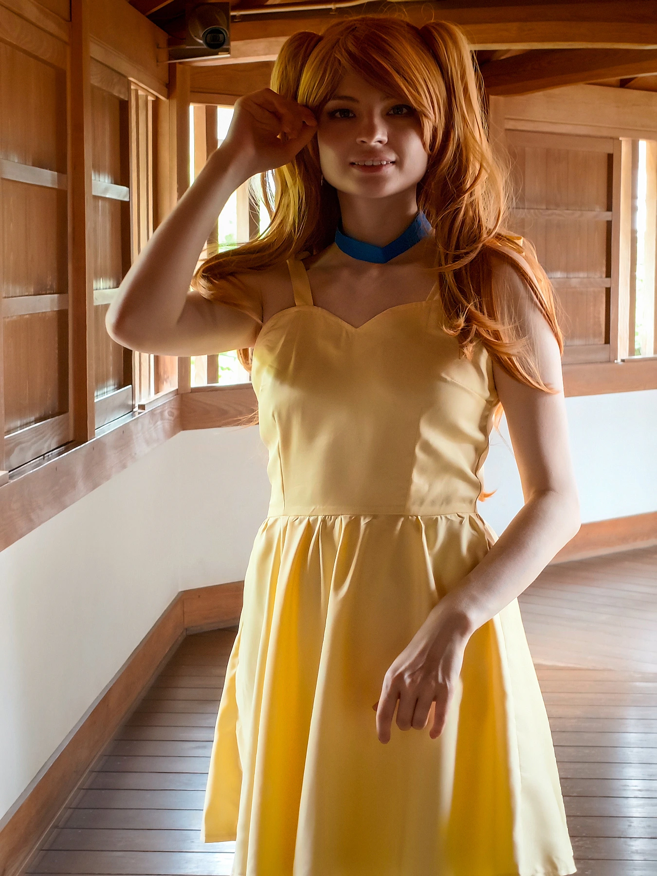 Asuka Langley cosplay in a yellow dress posing inside a traditional wooden corridor at Himeji Castle