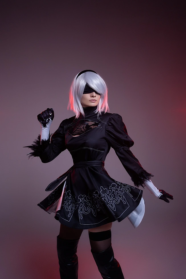 2B cosplay mid-turn with flowing skirt and red rim light, silver bob, black blindfold, NieR Automata motion photography