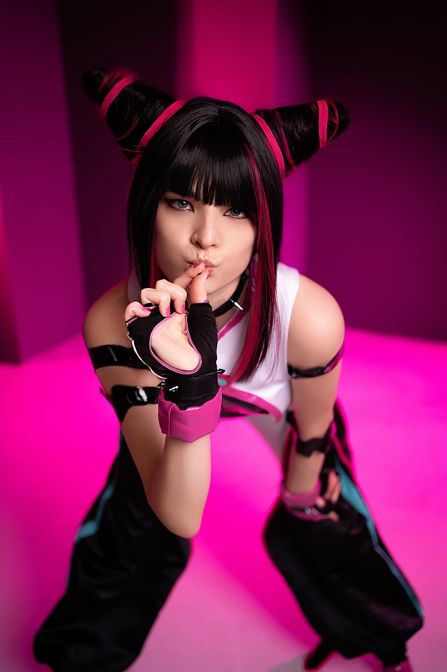 Juri Han cosplay close-up portrait, finger on lips gesture, pink neon studio lighting, horn buns hairstyle, Street Fighter villain