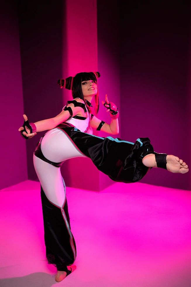 Juri Han cosplayer in full extension kick pose, barefoot, pink neon columns behind, glossy strap costume, horn buns, Street Fighter