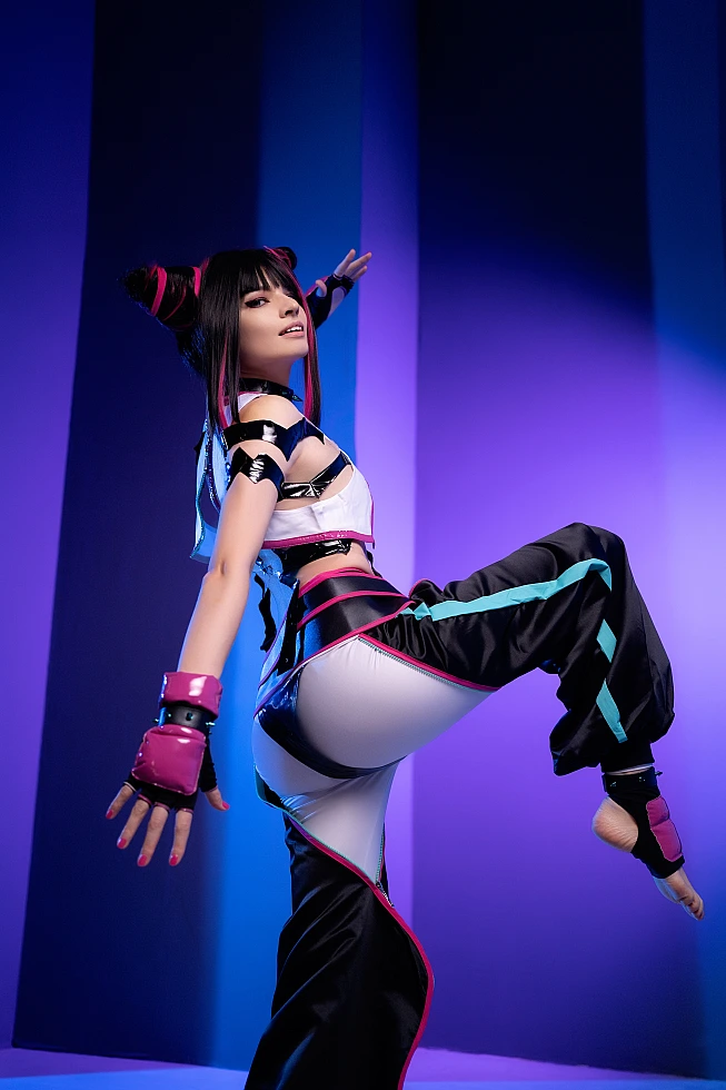 Juri Han cosplayer performing high kick in violet-blue neon lighting, horn buns hairstyle, glossy black costume, Street Fighter pose
