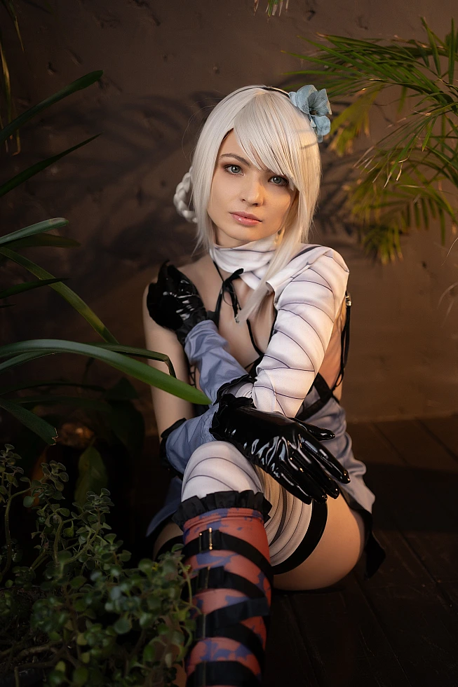 Kaine NieR Replicant cosplay intimate close-up portrait with warm lighting, pale hair, surrounding plants, bandaged arm and leg, black gloves