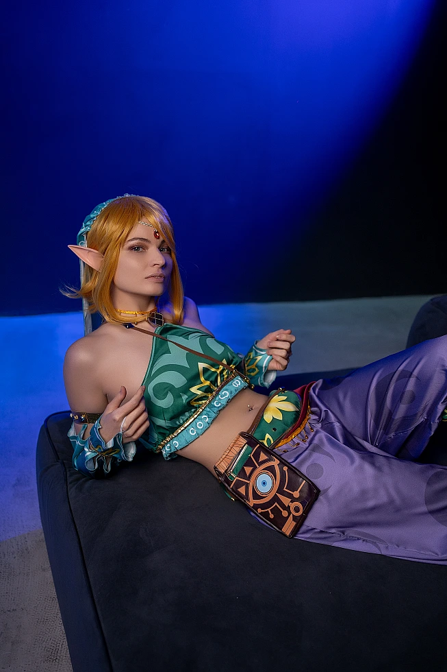 Gerudo Link cosplay reclining on sofa with blue studio background