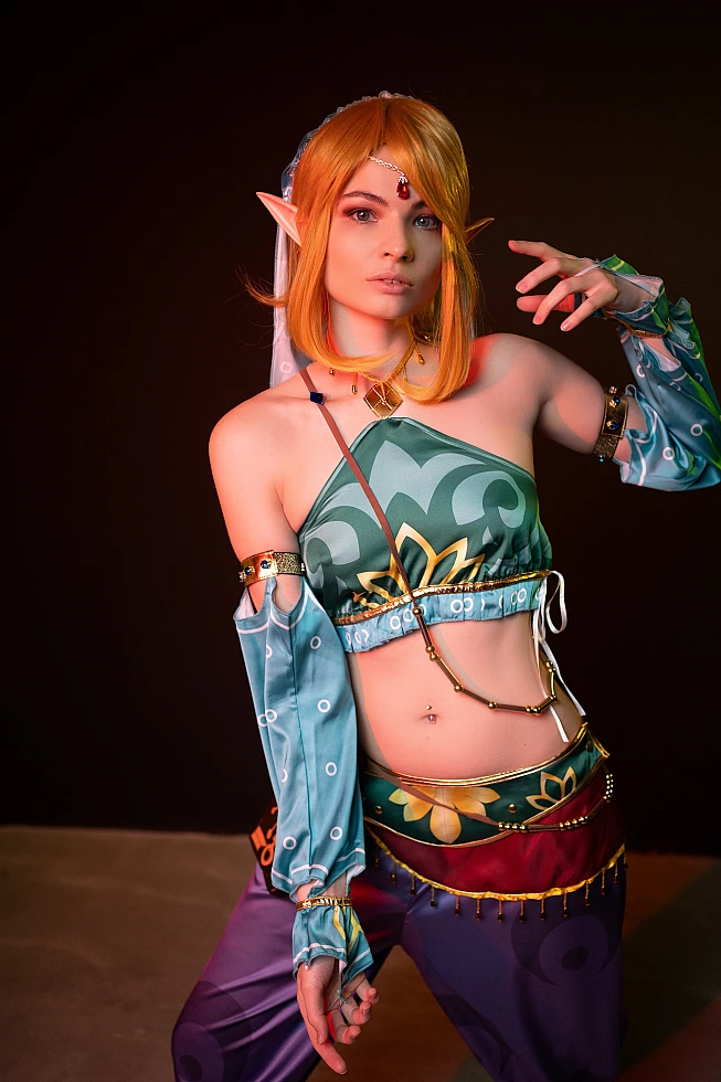 Gerudo Link cosplay standing with lifted hand and warm studio lighting