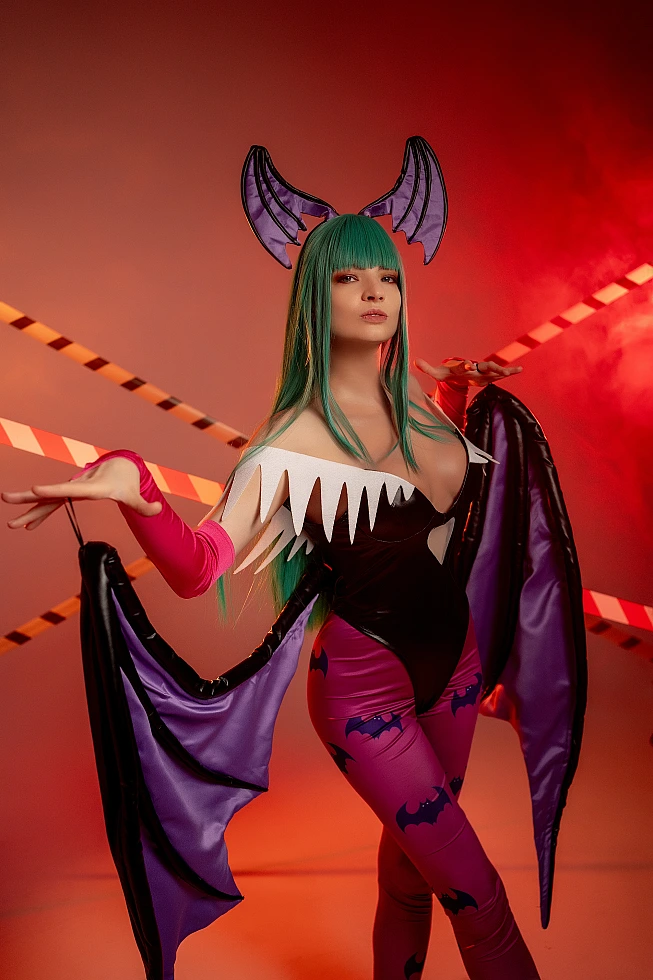 Morrigan Aensland cosplay raised hands pose, flowing succubus wing fabric, warm red studio lighting, glossy bodysuit