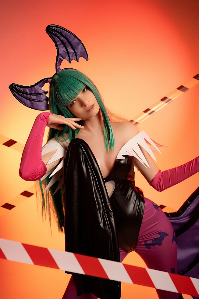 Morrigan Aensland cosplay warm orange studio, chin on hand pose, tilted head, crossed tape lines, succubus wings