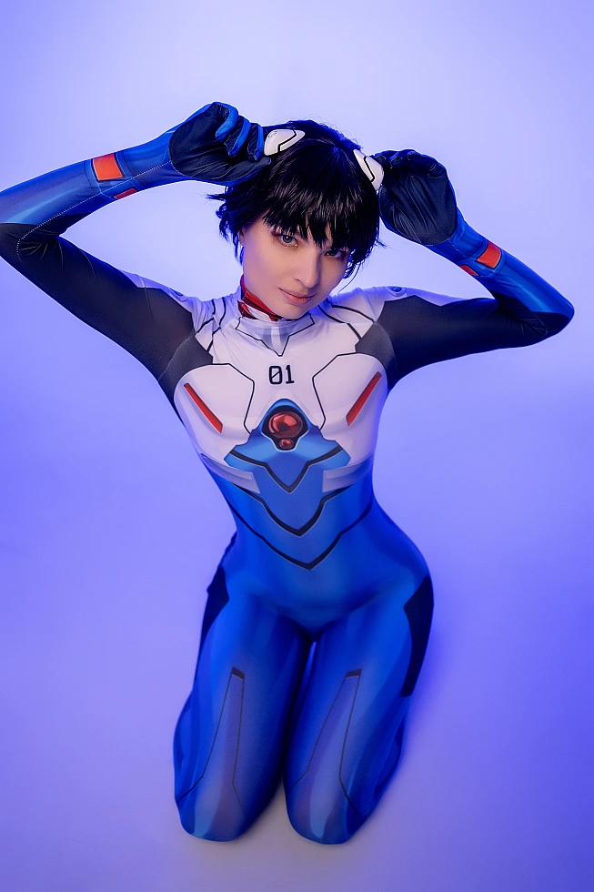Shinji Ikari cosplay kneeling pose in blue Evangelion plugsuit with neon studio lighting