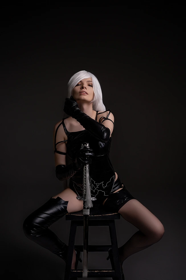 A2 cosplay NieR Automata seated stool wetlook latex corset shorts thigh-high stockings gloves sword vertical dramatic lighting