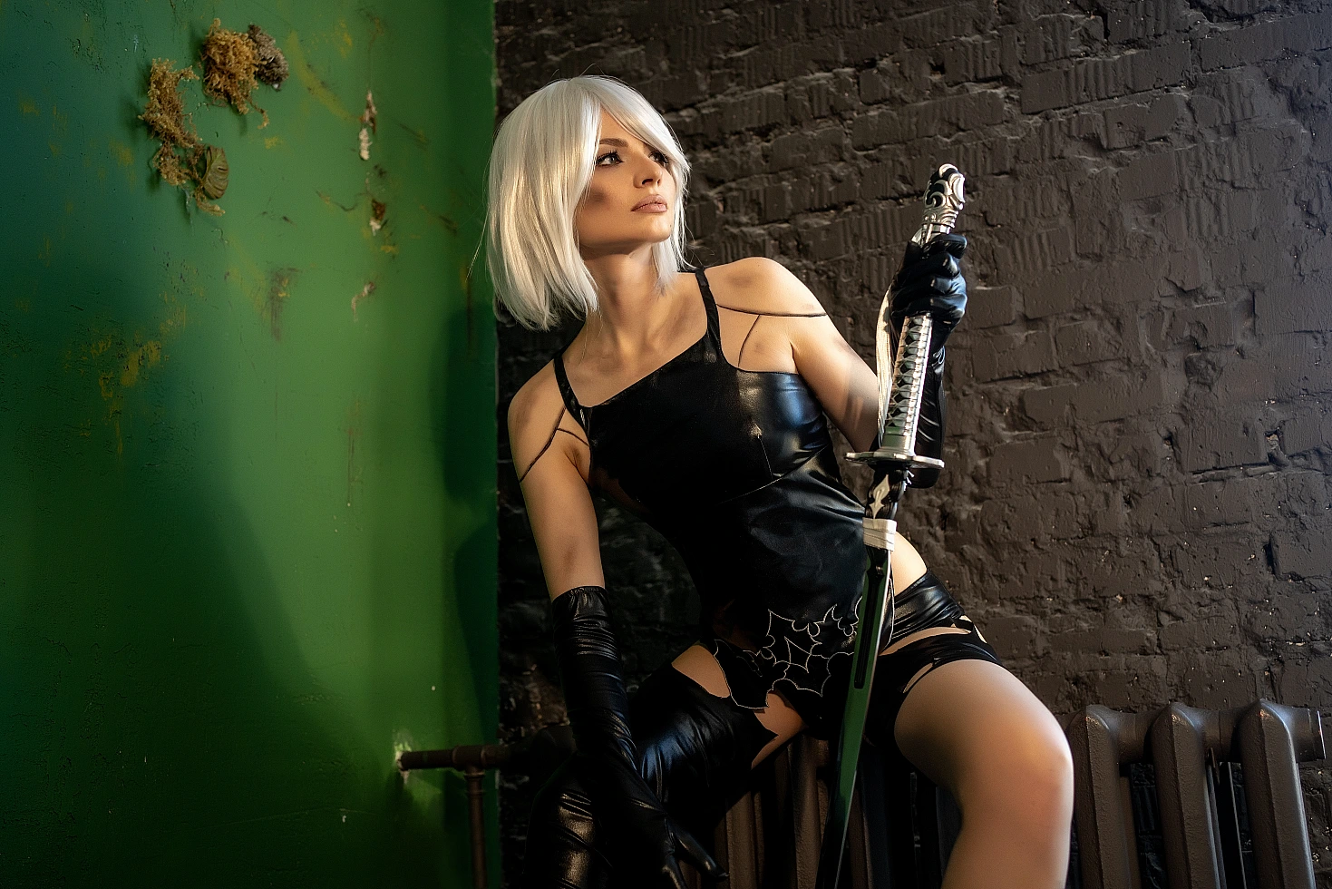 A2 cosplay NieR Automata angled pose, katana blade slightly raised, glossy black latex outfit, white bob wig, green wall and brick texture background, moody lighting