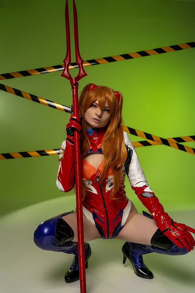 Asuka wide stance cosplay with spear prop on green background in latex plugsuit