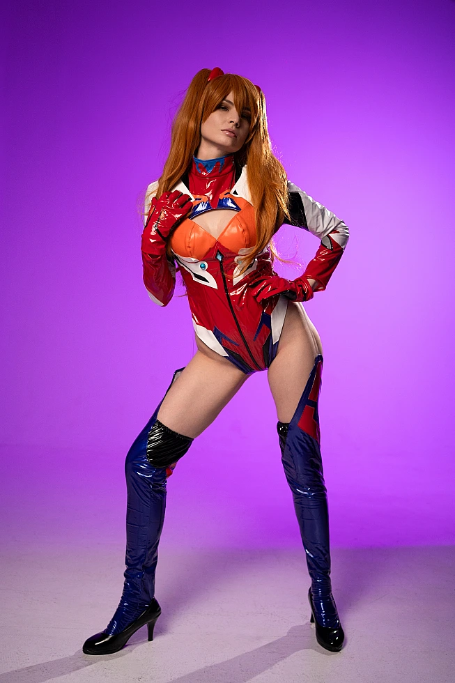 Asuka Langley power pose cosplay in latex plugsuit on purple studio background