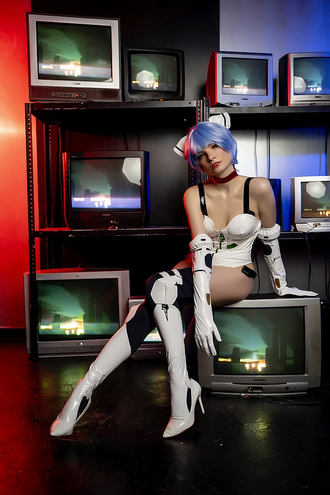 Rei Ayanami cosplay lounging on stacked CRT monitors in glossy white Evangelion plugsuit