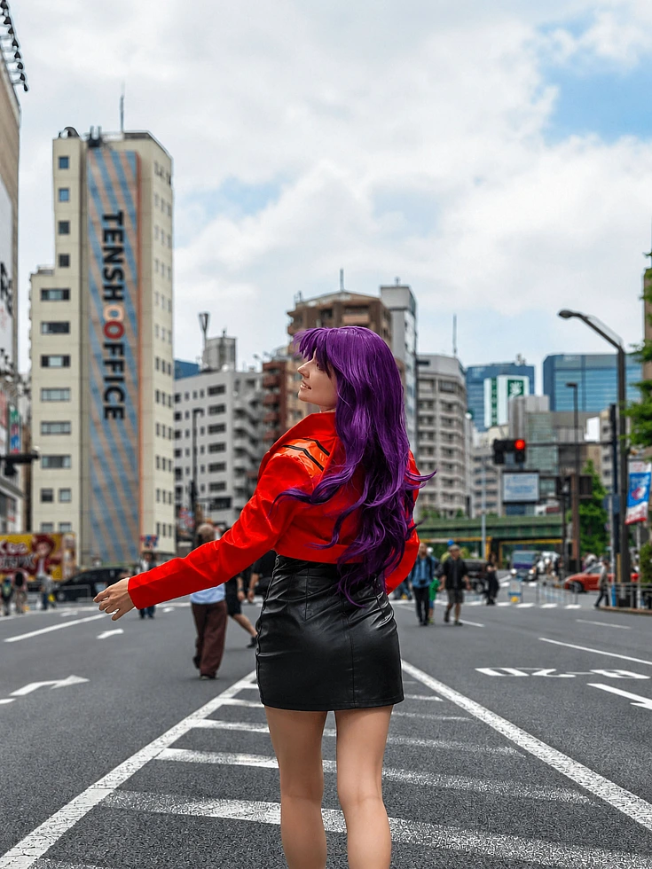 Misato Katsuragi cosplay walking on a Tokyo street in a red jacket, black skirt and long purple hair