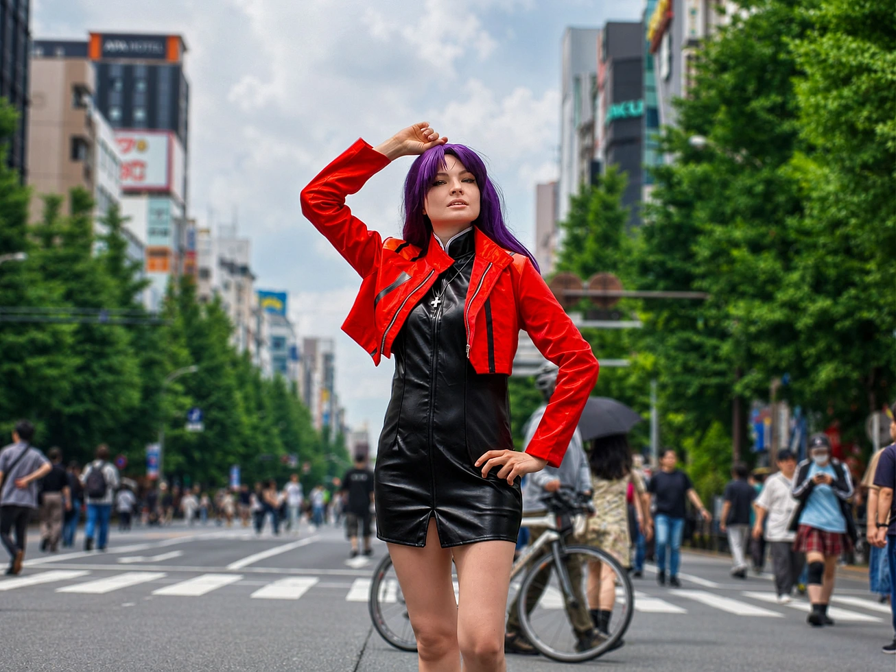 Full-body Misato Katsuragi cosplay posing on an Akihabara street in a red jacket and black dress with purple hair