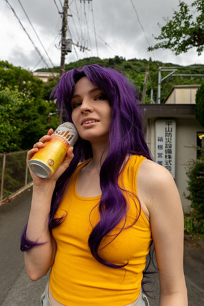 Misato Katsuragi casual cosplay holding a drink can outdoors with long purple hair, yellow top and mountain scenery