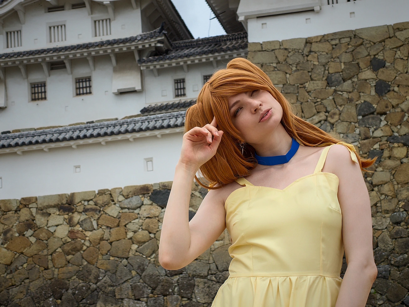 Close-up Asuka Langley cosplay portrait in a yellow summer dress with Himeji Castle walls in the background